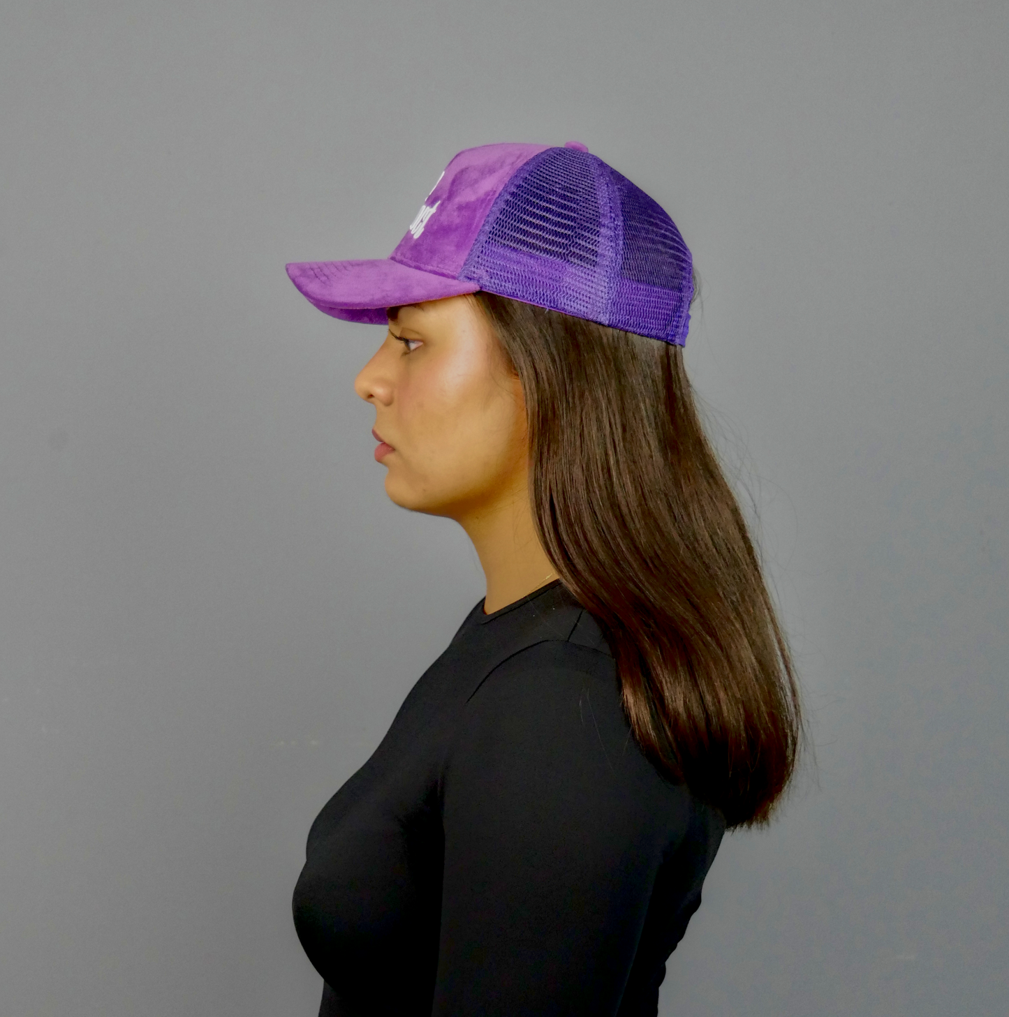 KELIX Velours Cap in Lila mit weiรem 'be distinct' Stick โ Frontansicht einer Person, die die Kappe trรคgt, zusammen mit einer Seitenansicht der Kappe und einer weiteren Person im schwarzen Hoodie mit lila Kappe.