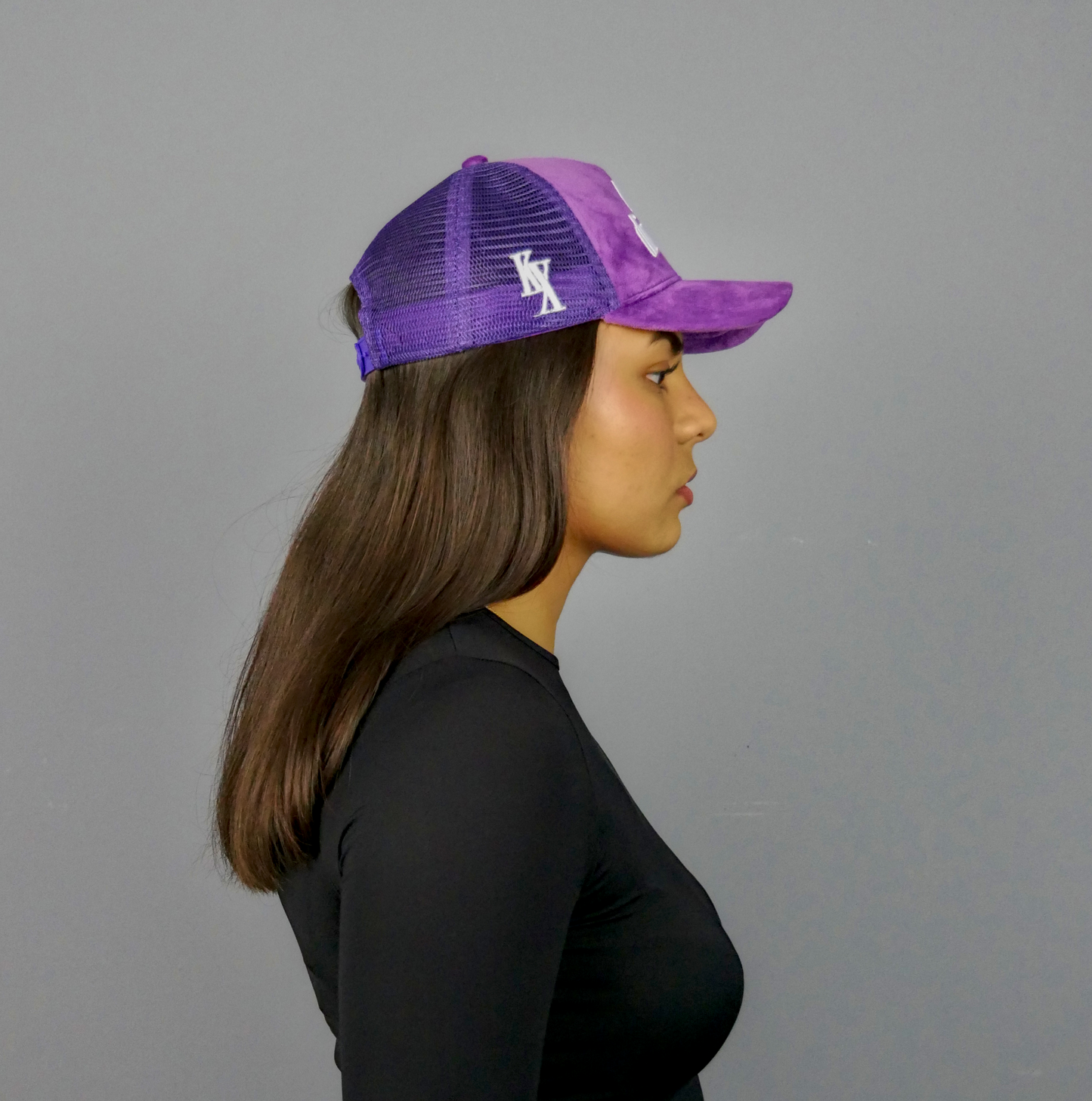 KELIX Velours Cap in Lila mit weiรem 'be distinct' Stick โ Frontansicht einer Person, die die Kappe trรคgt, zusammen mit einer Seitenansicht der Kappe und einer weiteren Person im schwarzen Hoodie mit lila Kappe.