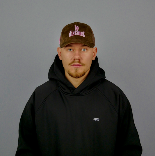 KELIX Velours Cap in Braun mit pinkem 'be distinct' Stick – Seitenansicht und Frontansicht einer Person, die die Kappe trägt, dazu das Logo auf dem schwarzen Hoodie sichtbar.